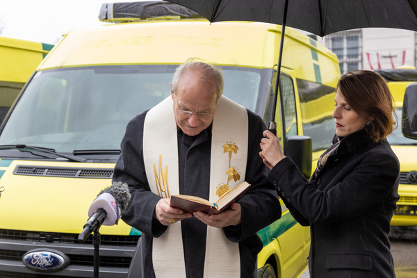 BM Edtstadler hält Kardinal Schönborn den Regenschirm während der Segnung
